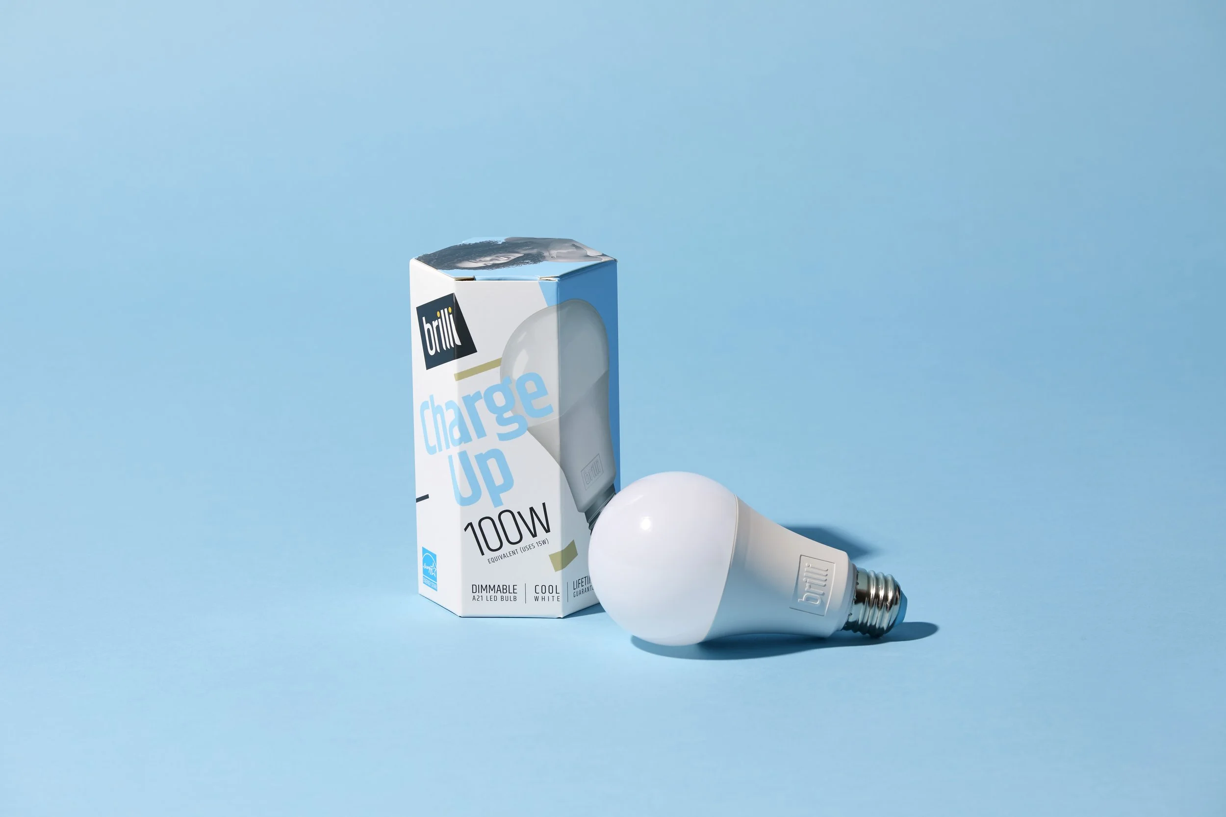 A white LED light bulb next to its packaging box on a light blue background.