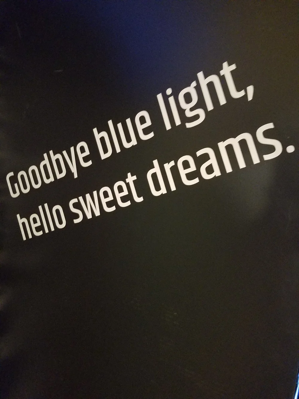 A black wall with white text that reads, 'Goodbye blue light, hello sweet dreams.'