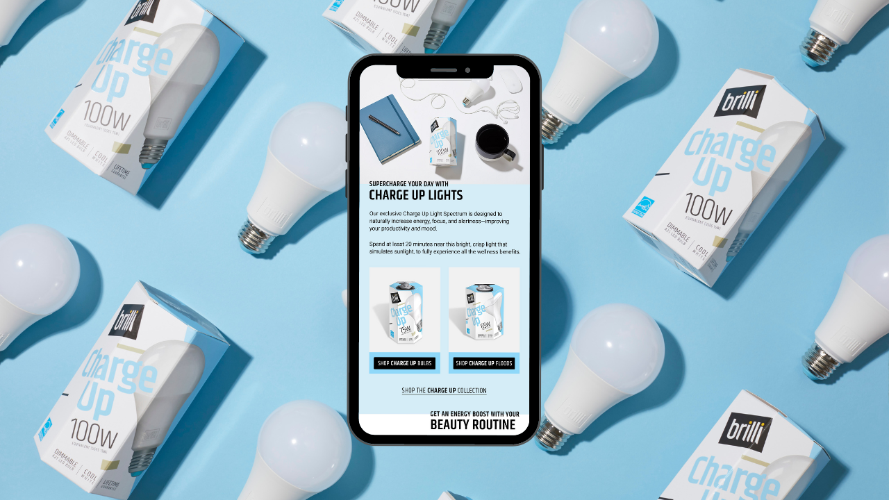 Smartphone on a blue surface surrounded by light bulbs and boxes of brilli Charge Up 100W light bulbs, with the screen displaying product details and options.