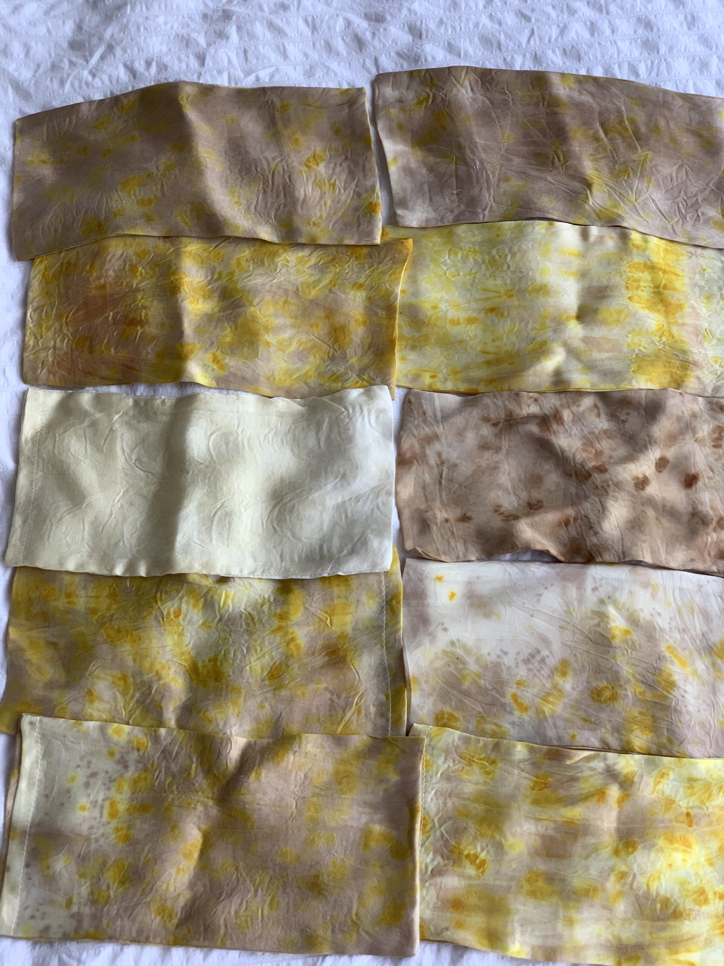 A collection of crumpled tissues or cloths with yellow and brown stains, laid out on a white surface.