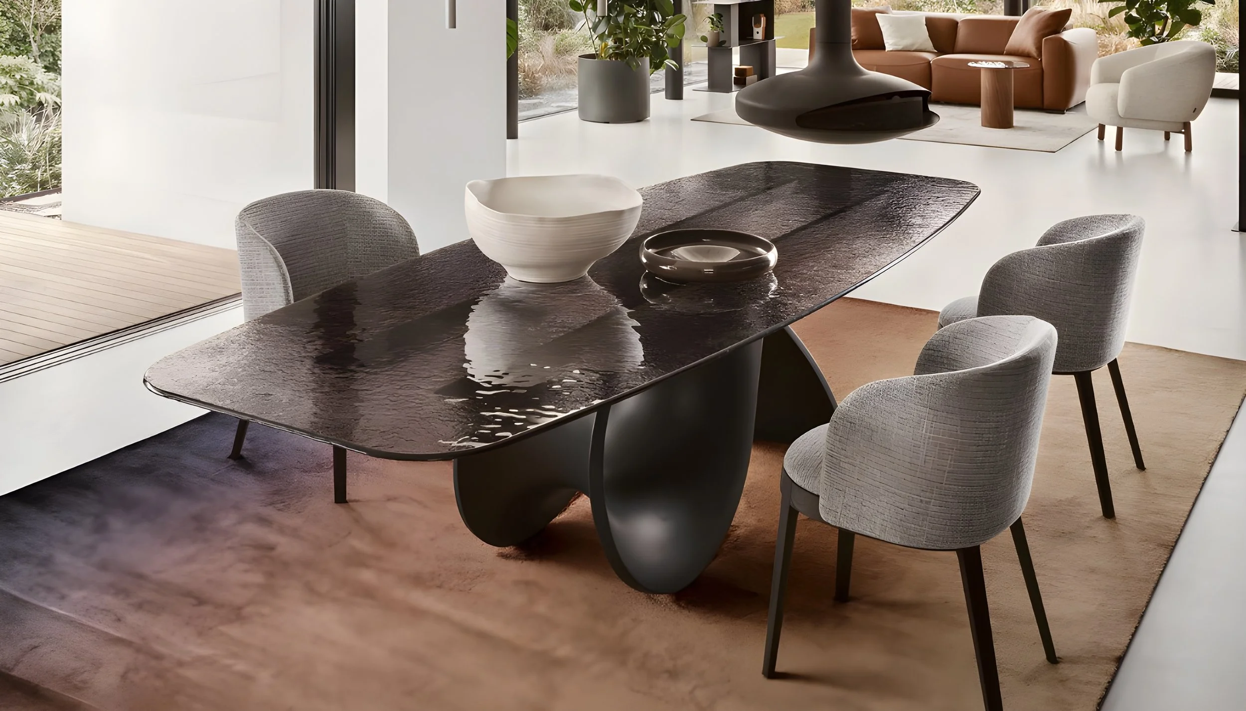 Moderner Esszimmertisch mit vier grauen Stühlen, dekorative Keramikkörbe, im Hintergrund ein Wohnzimmer mit braunem Sofa, weißem Armchair, Pflanzen und großen Fenstern.