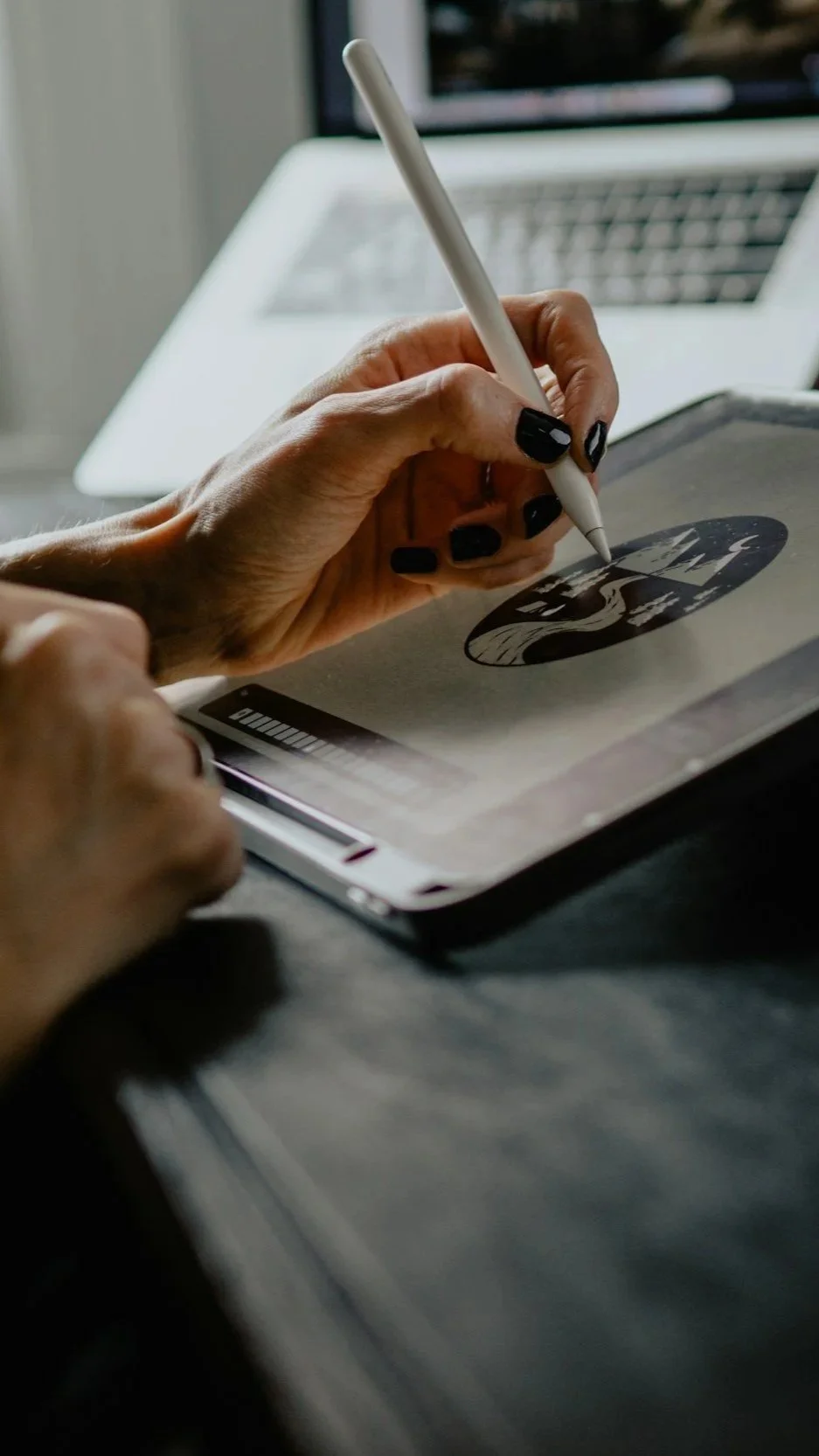 A person drawing a digital logo illustration on a tablet with a stylus.