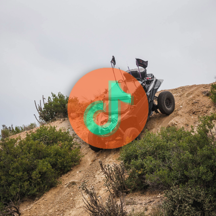 A golf cart on a dirt trail on a hillside with shrubs and plants, overlaid with a semi-transparent TikTok logo.