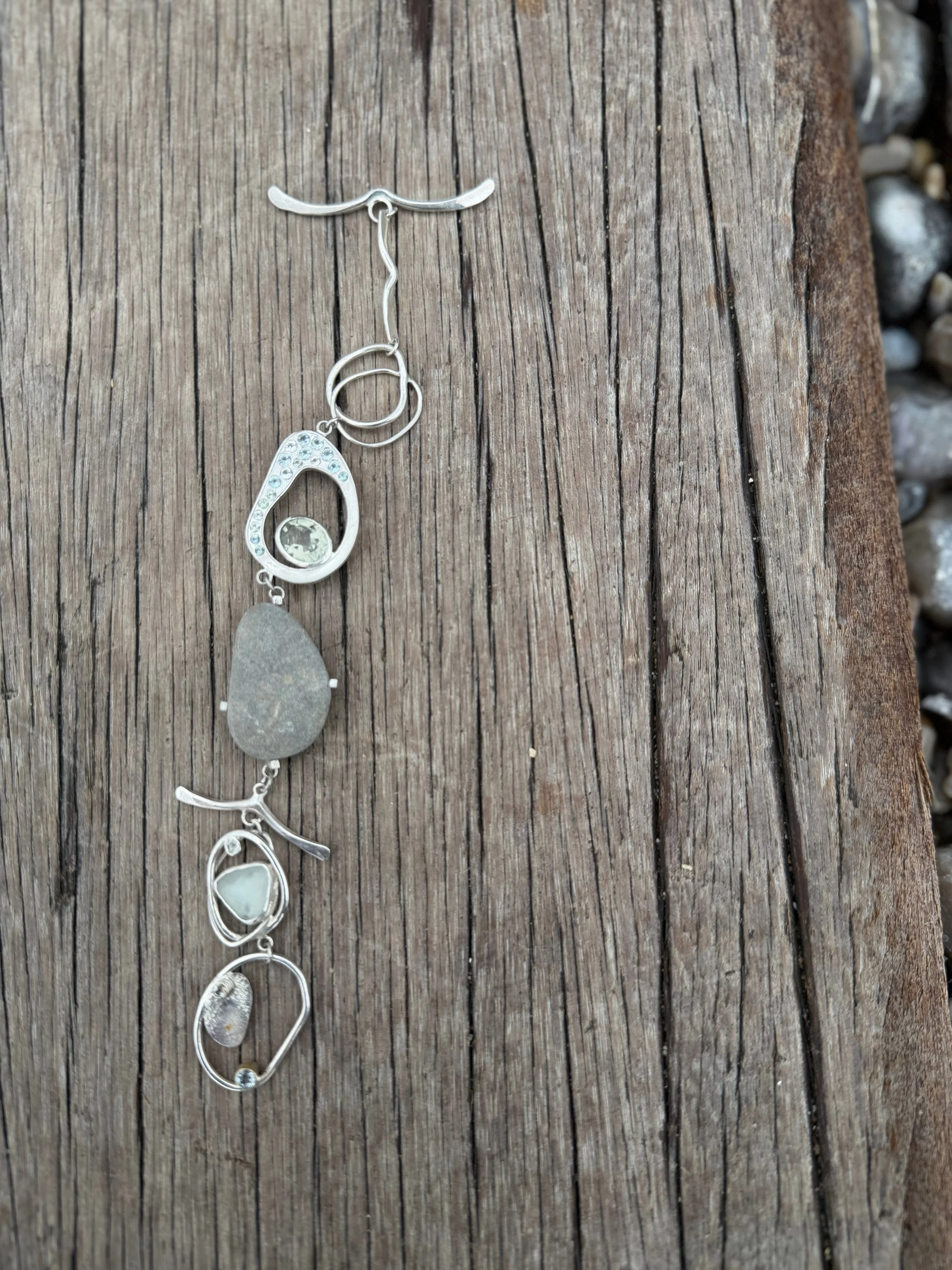 Statement Jewellery by Becca Charlo - A one-of-a-kind bracelet featuring a naturally weathered pebble, flush-set sapphires, amethyst, aquamarine and topaz. Inspired by coastal walks and treasured finds, the piece combines traditional goldsmithing tec