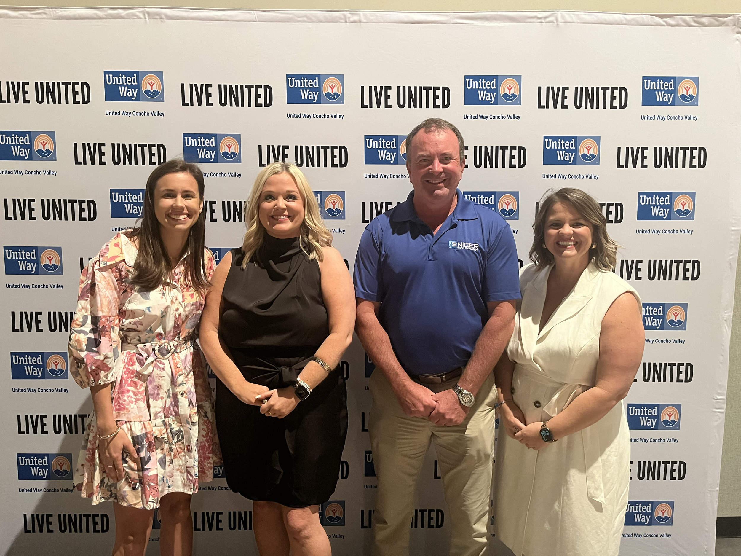Four people standing in front of a United Way Concho Valley backdrop at an event, smiling for the camera.