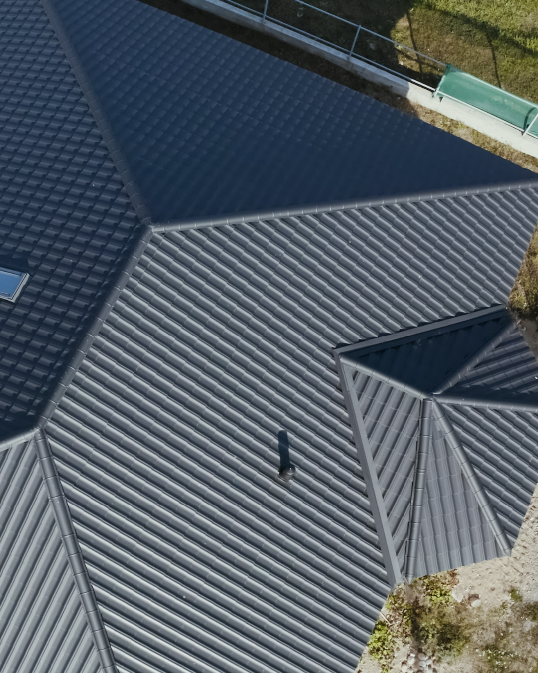 Aerial view of a building with multiple metal roofs in shades of gray and silver.