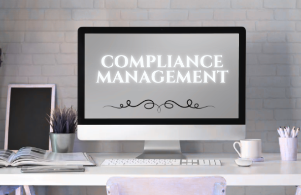 Compliance Management Services on a white background, on a modern white desk with books, a cup, and office supplies.