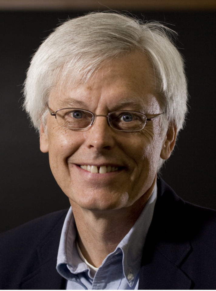 Photo of Stuart Vyse, a man with white hair, glasses, wearing a dark blazer and light blue shirt, smiling at the camera.