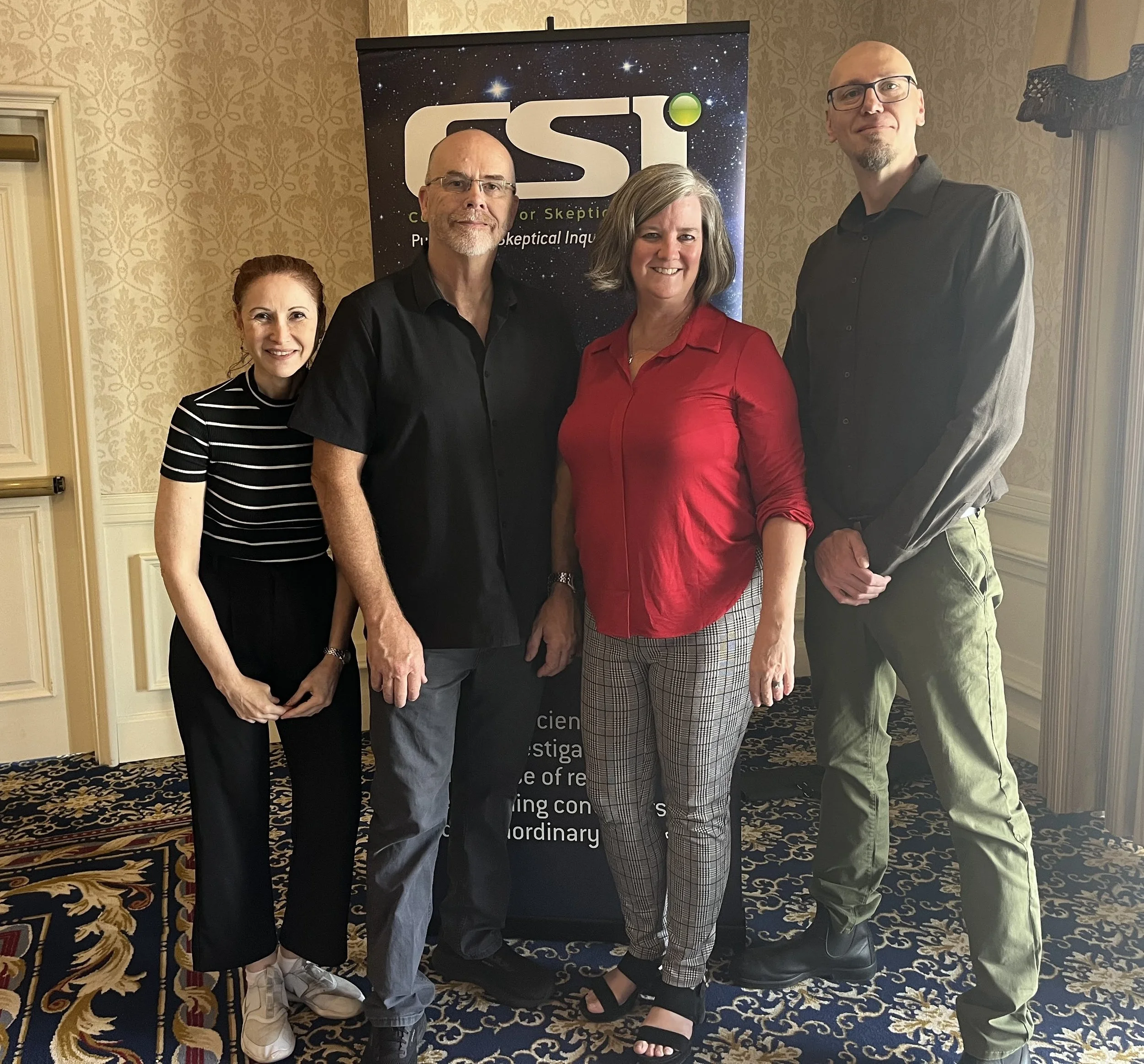 Pasternak, Hall, Dyer and Schmaltz standing in front of a black poster with a starry background advertising CSICon. From LiliCon 2024.