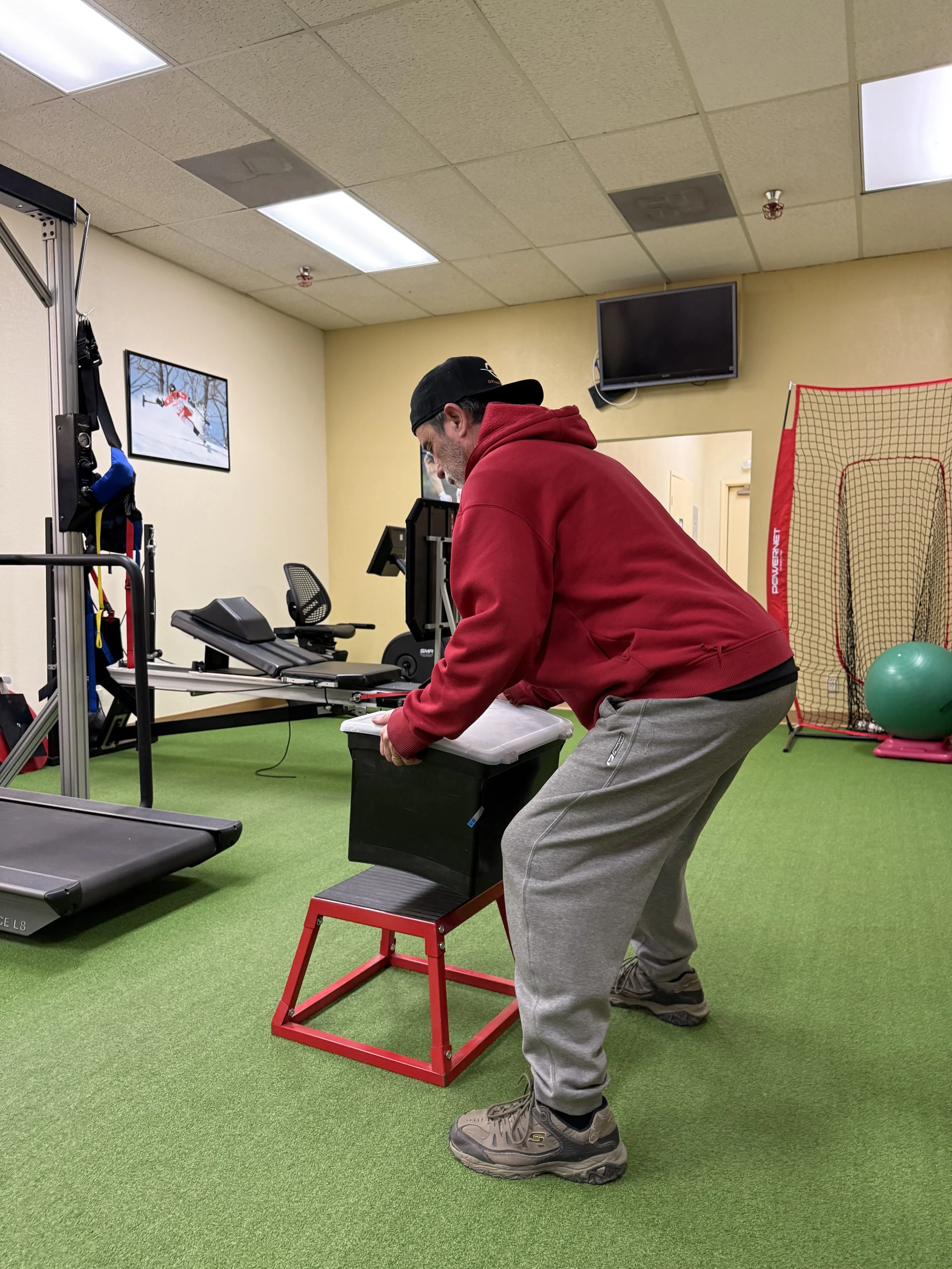 A healthcare worker assisting an elderly woman with arm exercises in a bright, homey setting.