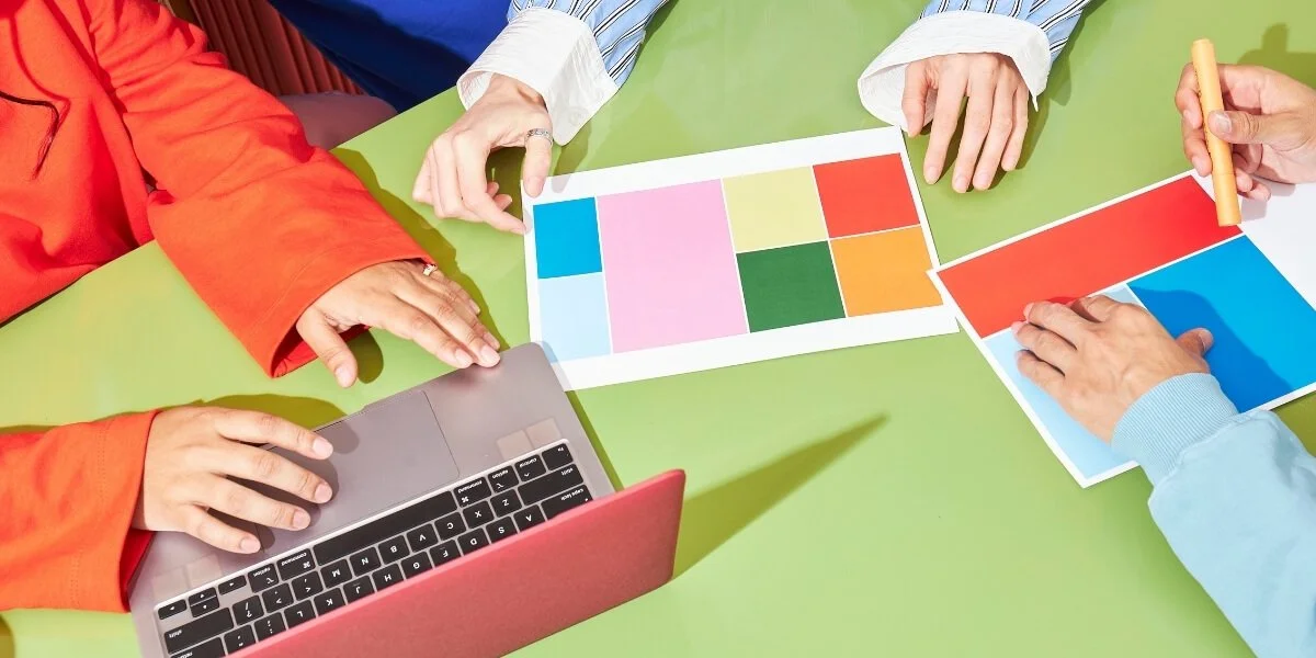 Hands holding printed color palettes.