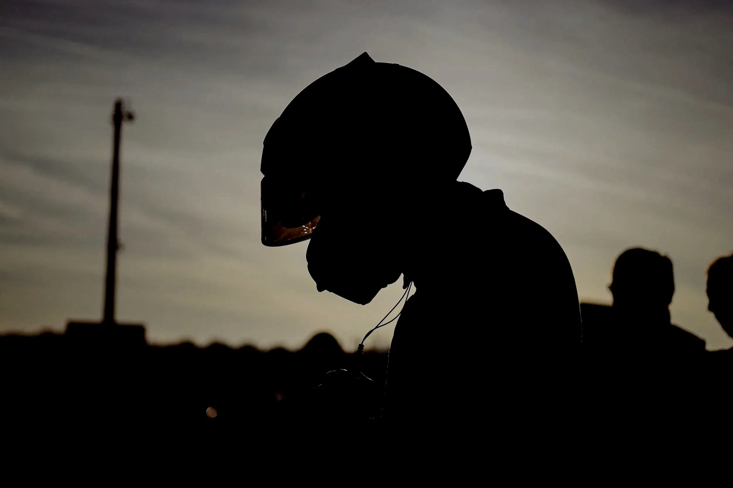 Silhouette of a person wearing a helmet with a cloudy sky in the background.