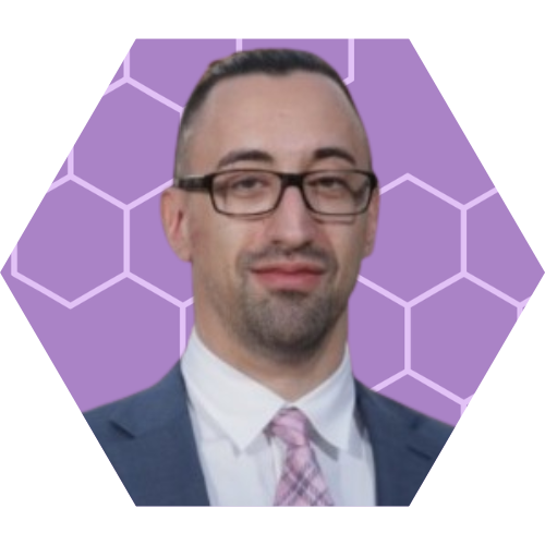 A professional man with glasses, wearing a suit and pink tie, standing in front of a purple background with a hexagonal pattern.