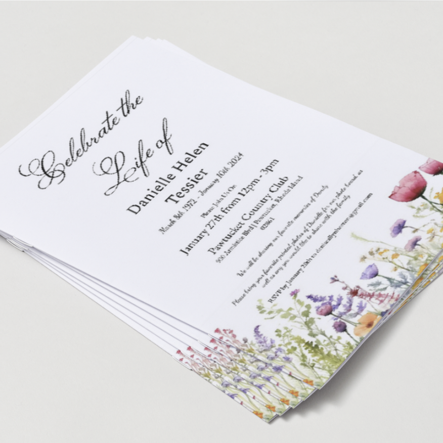 A stack of funeral programs with floral border designs on white paper.