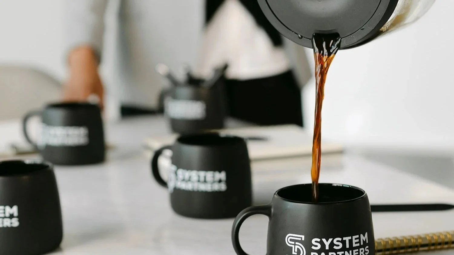Coffee being poured into System Partners mug during client meeting.