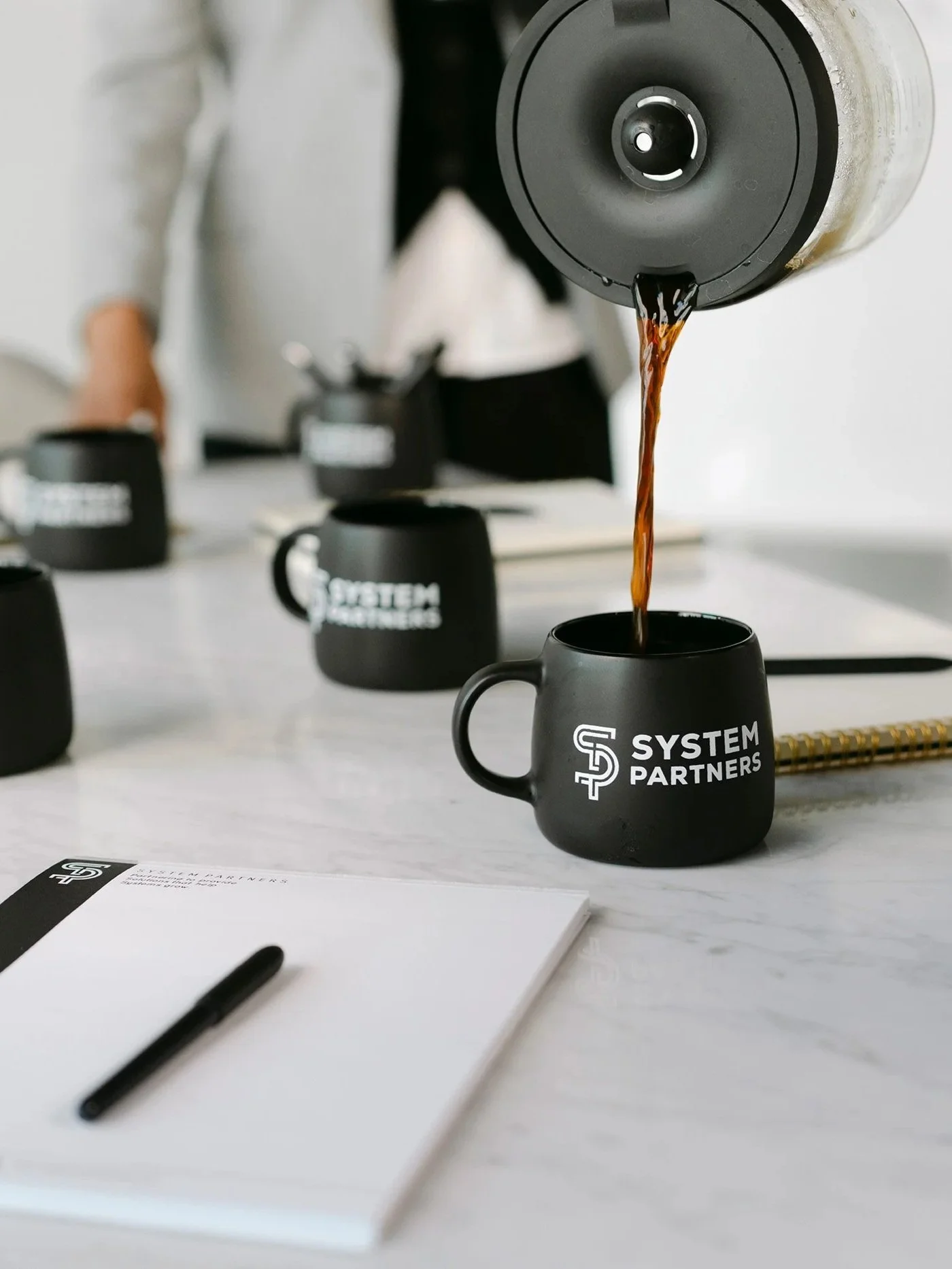 Coffee being poured into System Partners mug during client meeting.
