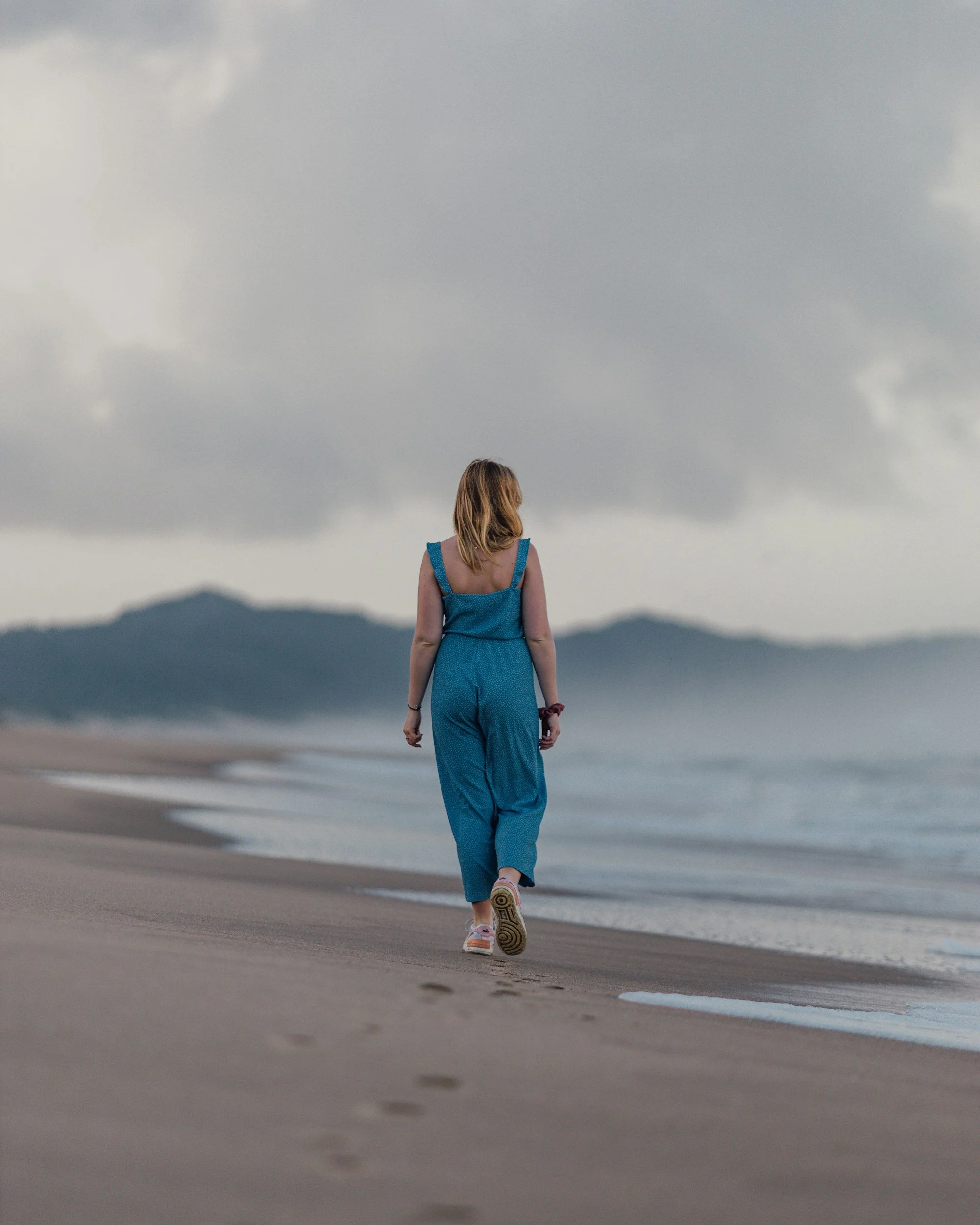 Woman sitting quietly near the ocean in Carmel-by-the-Sea, representing nervous system regulation and somatic therapy for emotional pattern release on the Monterey Peninsula.