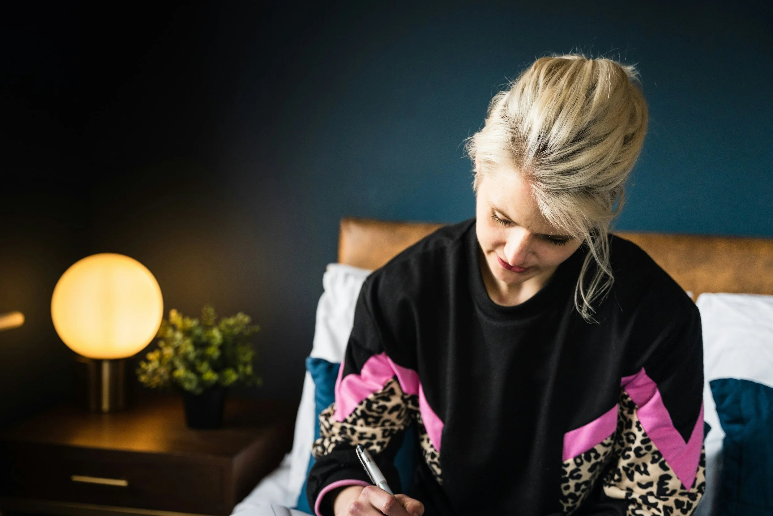 Woman sitting thoughtfully by a window with soft light, representing ketamine-assisted psychotherapy for self-aware people who feel stuck in healing in Carmel-by-the-Sea