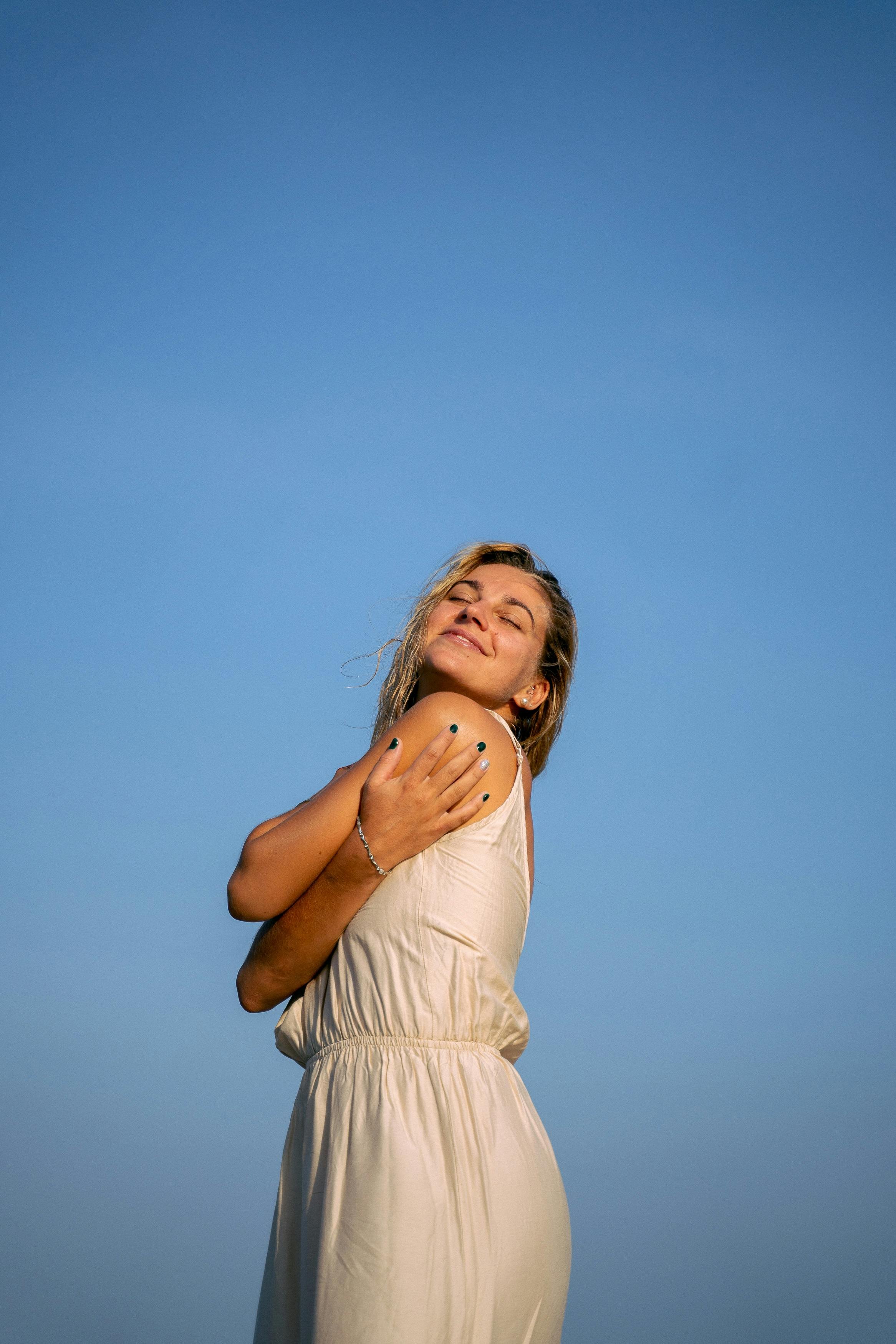 woman holding herself at the beach after experiencing embodied psychedelic support therapy in Carmel, California.