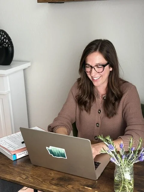 Image of woman with glasses at desk on laptop
