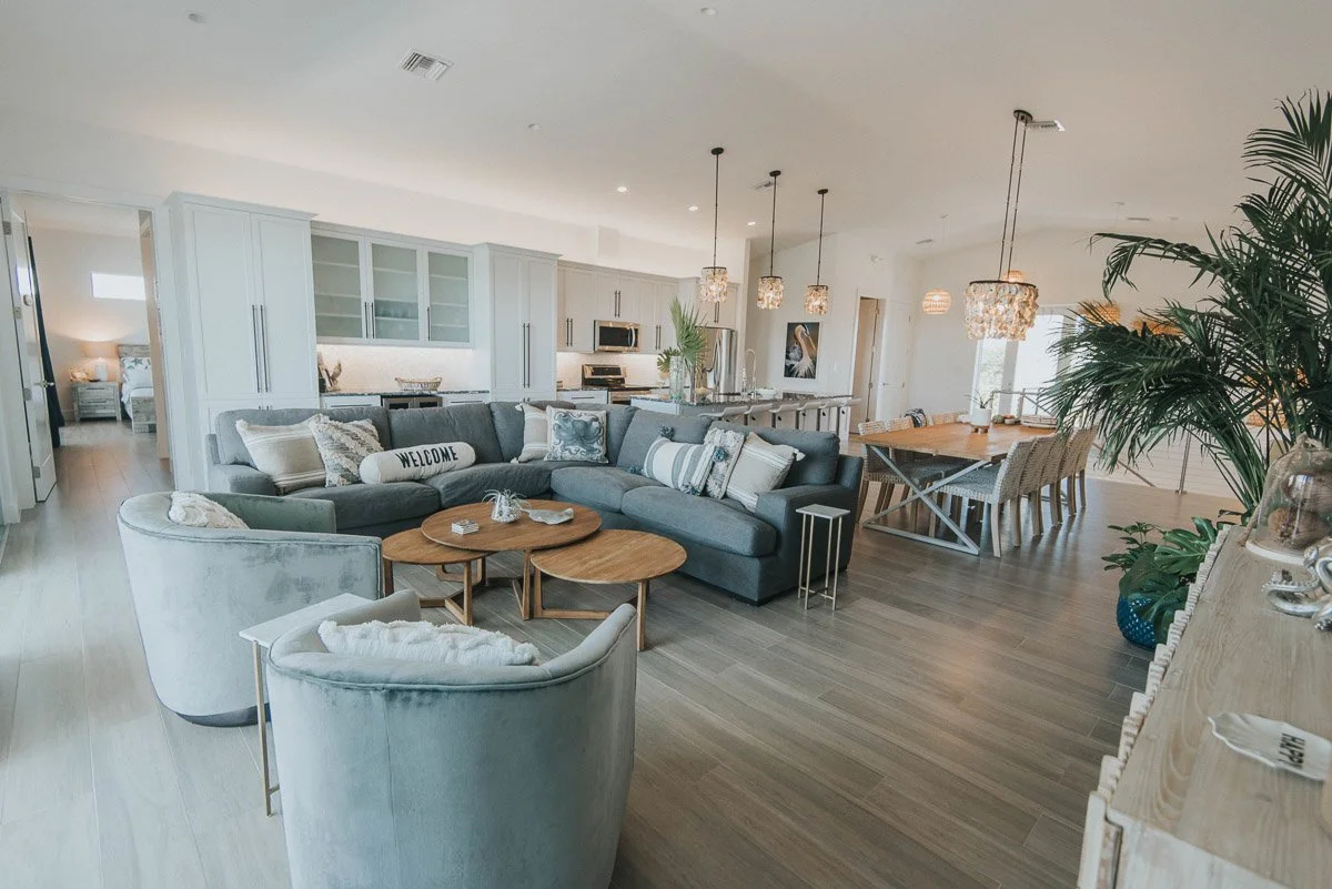 Open-concept living room and kitchen with modern decor, large sectional sofa, and light wood flooring.