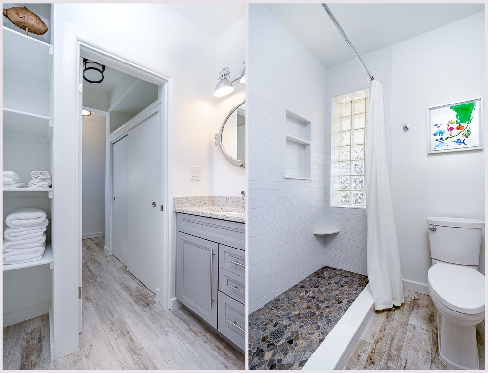 A side-by-side view of a bathroom. The left side shows a vanity with a granite countertop, a round mirror, and shelves with towels. The right side features a walk-in shower with a glass block window, built-in shelves, a shower curtain, and a toilet.