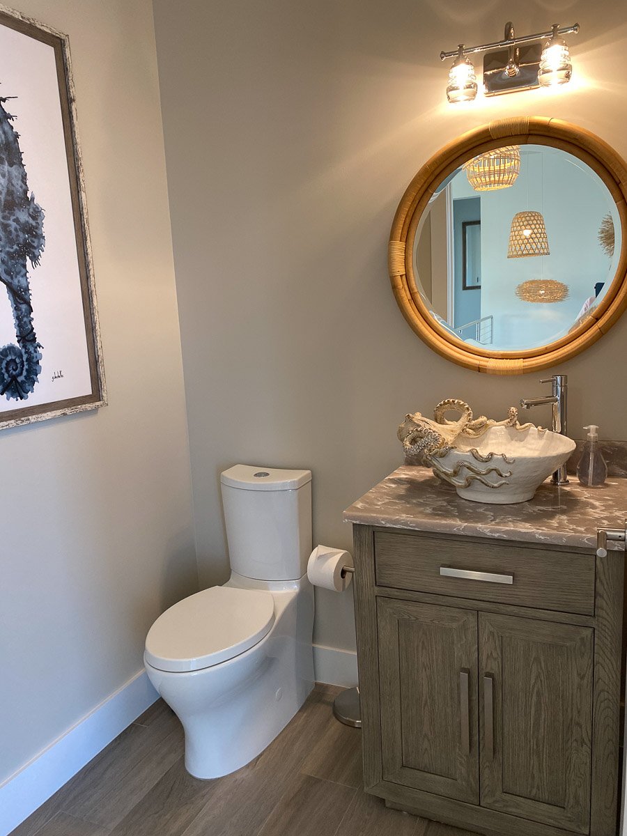 Bathroom featuring a toilet, a wooden vanity with a marble countertop, a decorative shell sink, a mirror, and wall lights with three bulbs.