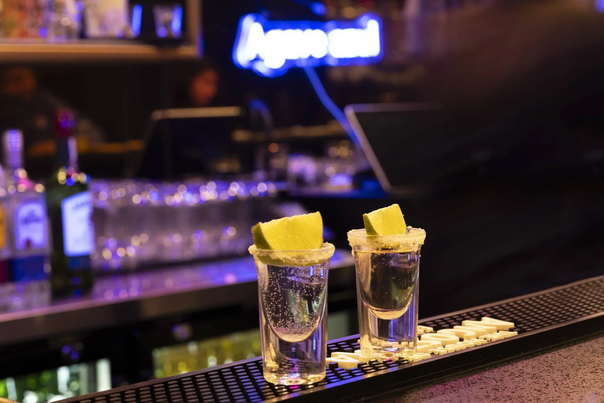 two tequila shots with lime on a bar