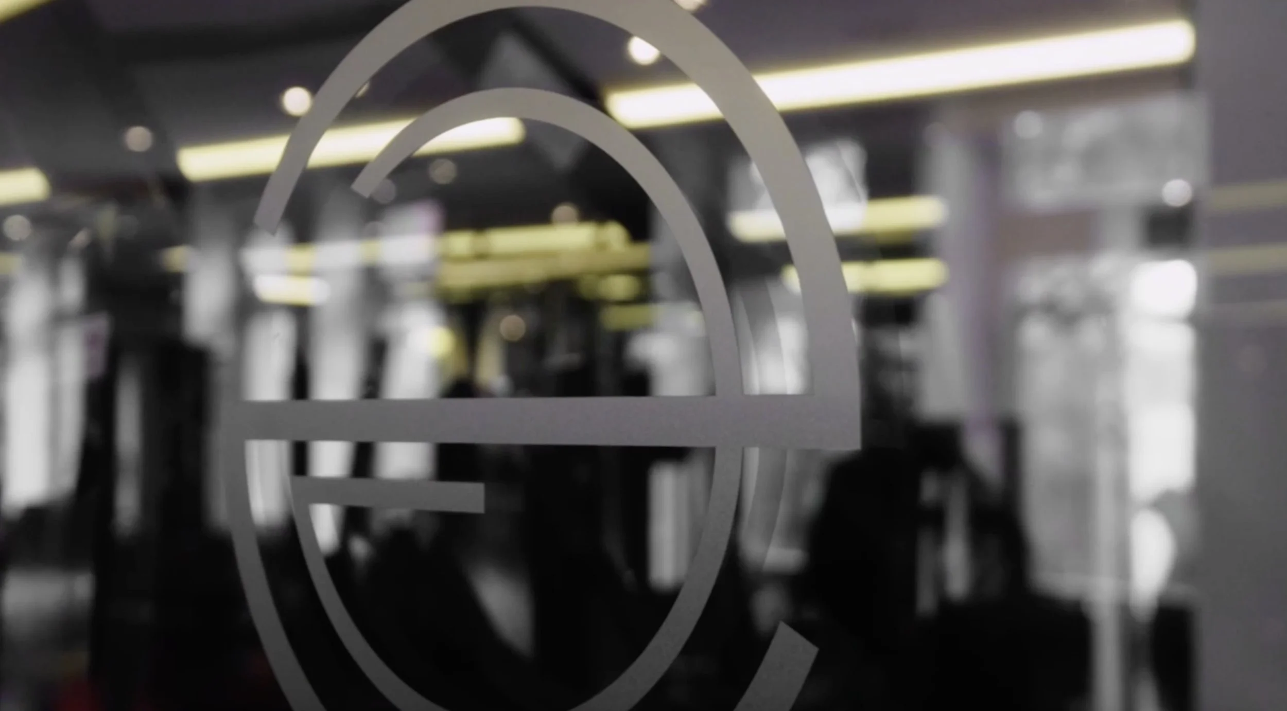 View of a GitHub logo on a glass window with blurred background of an office or workspace.