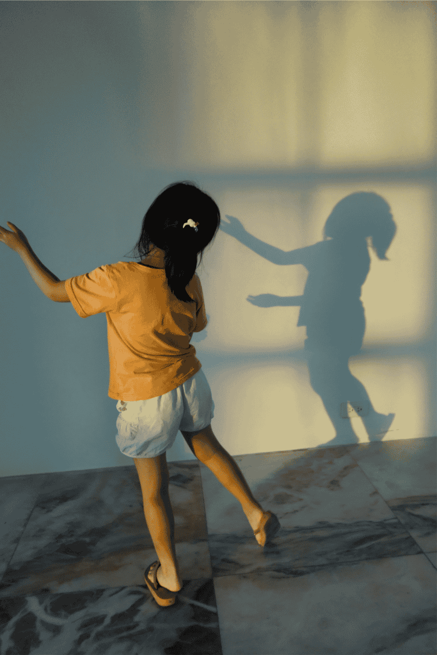 Child playing and watching her shadow follow her