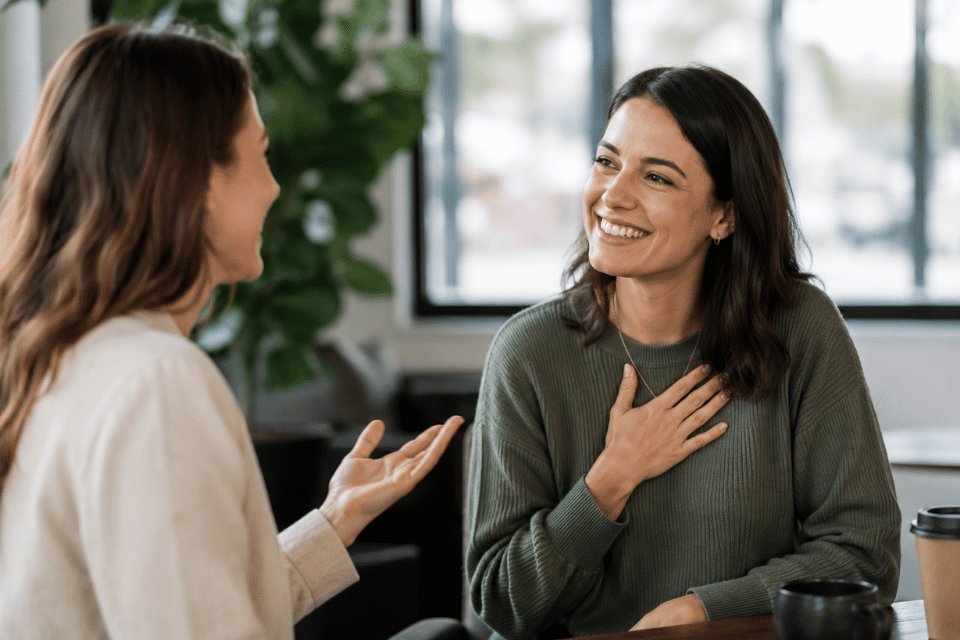 Two women in a conversation while one is complimenting the other, and the receiver of the compliment showing gratitude for it.