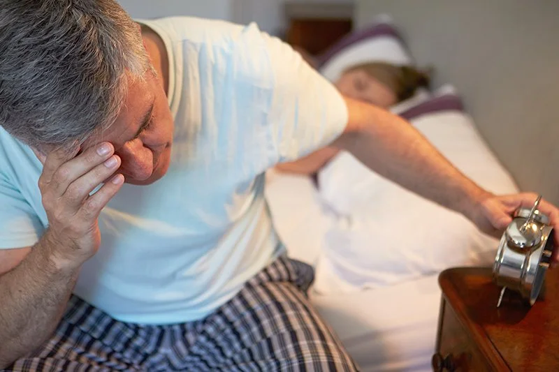 Man waking up tired with morning exhaustion, a common symptom of sleep apnea, for Northwest Ohio Sleep Solutions in Maumee Ohio