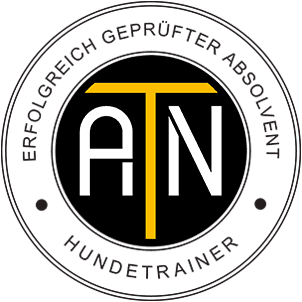 Logo for a dog trainer certification program, featuring the initials 'A T N' within a black circle with yellow and white elements and German text around the edge.