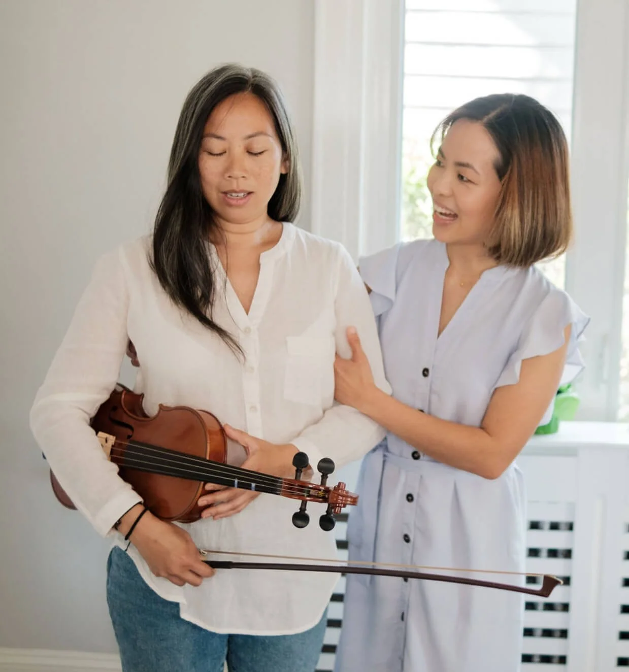 Aik helping woman with eyes closed holding Violin