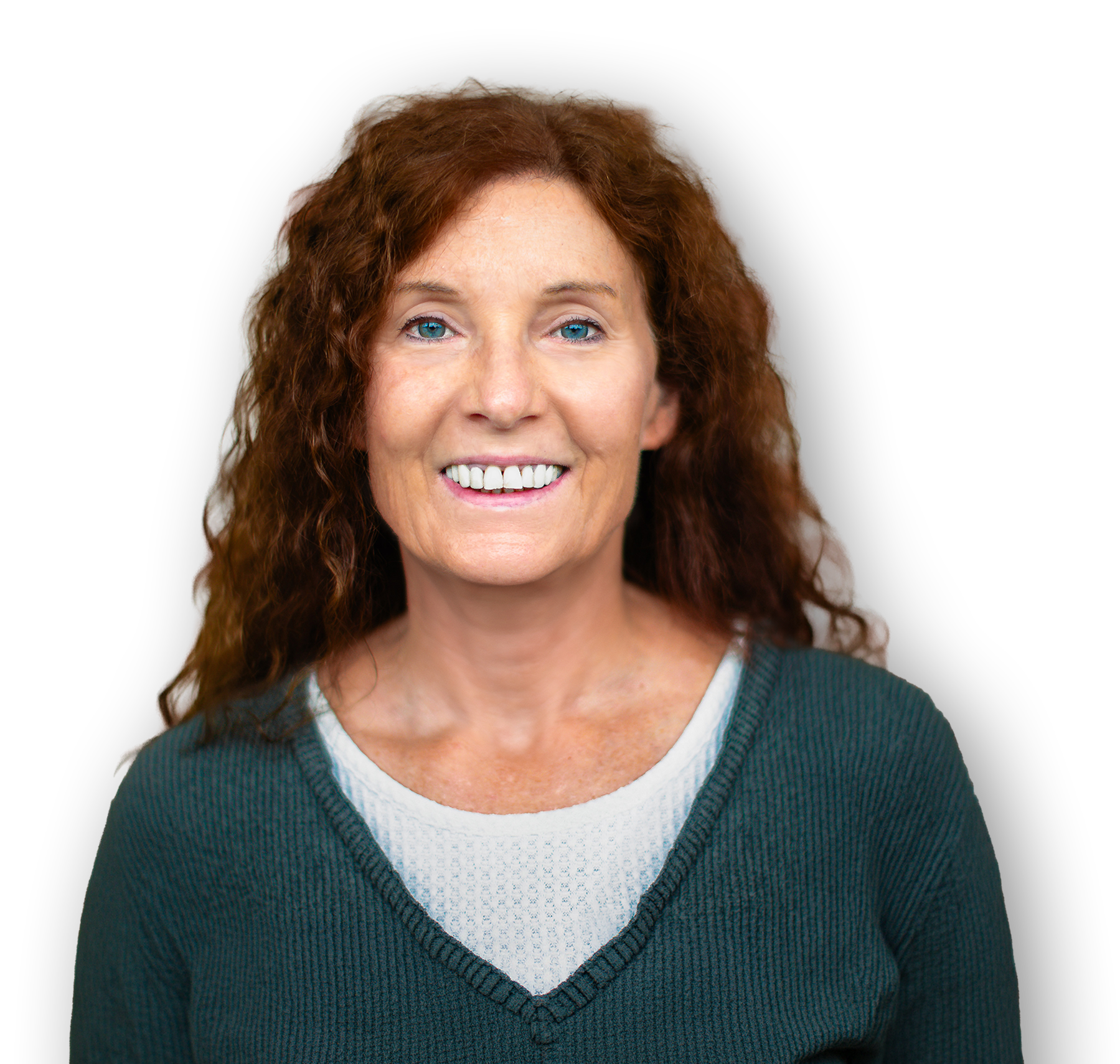 Close-up of a smiling woman with blue eyes and curly red hair, wearing a teal sweater and a white shirt, against a black background.