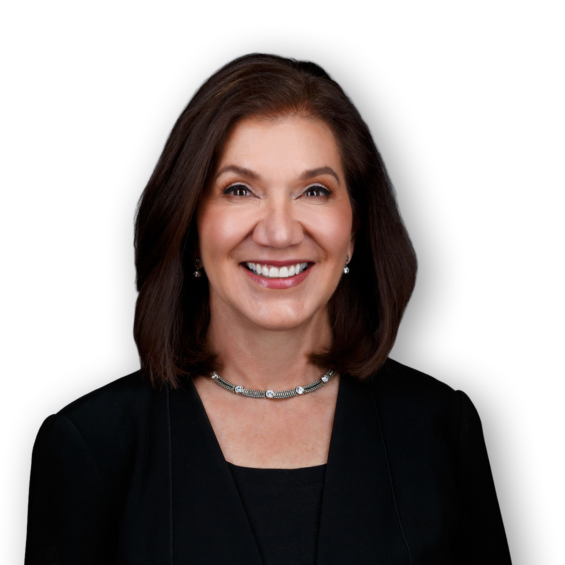 A middle-aged woman with shoulder-length brown hair and light skin, smiling, wearing a black blazer and a silver jewelry set including earrings and a necklace, against a black background.