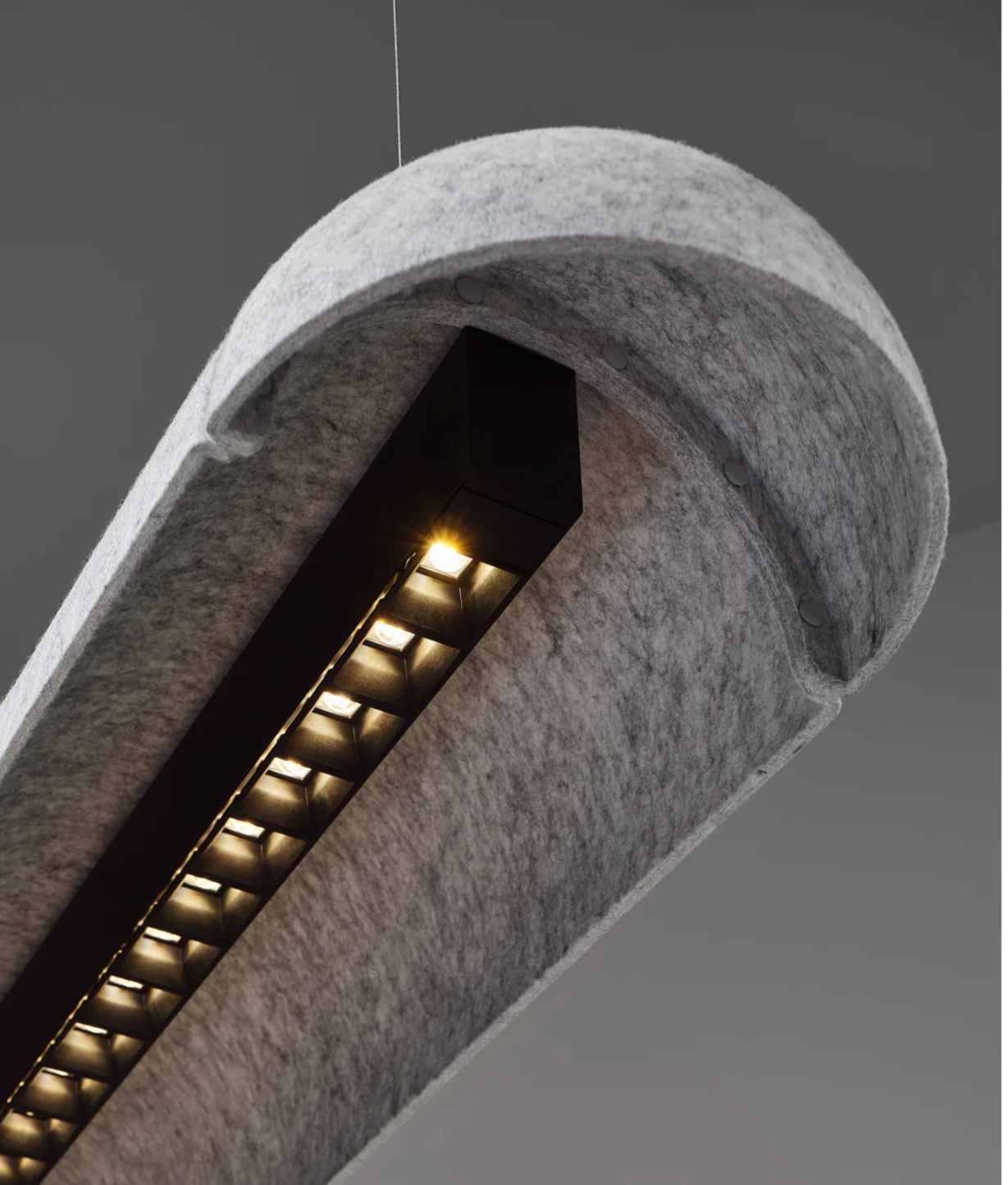 Close-up of a modern outdoor light fixture mounted in a concrete wall, with multiple small square lights illuminated underneath a rounded overhang.