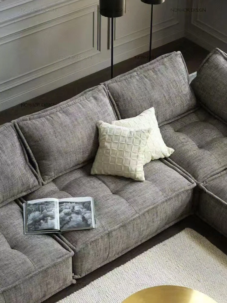 Gray fabric sectional sofa with white decorative pillows, open magazine, in a living room with wainscoting walls and a cream rug.