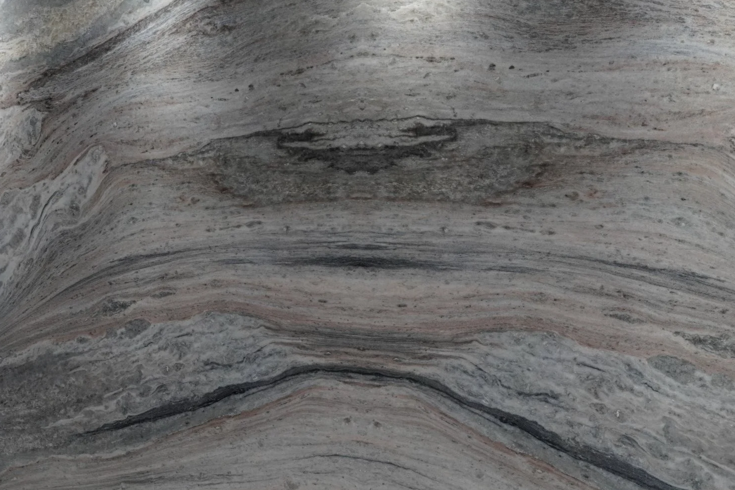 Close-up of a marble surface with layered gray, black, and pinkish-brown veins.