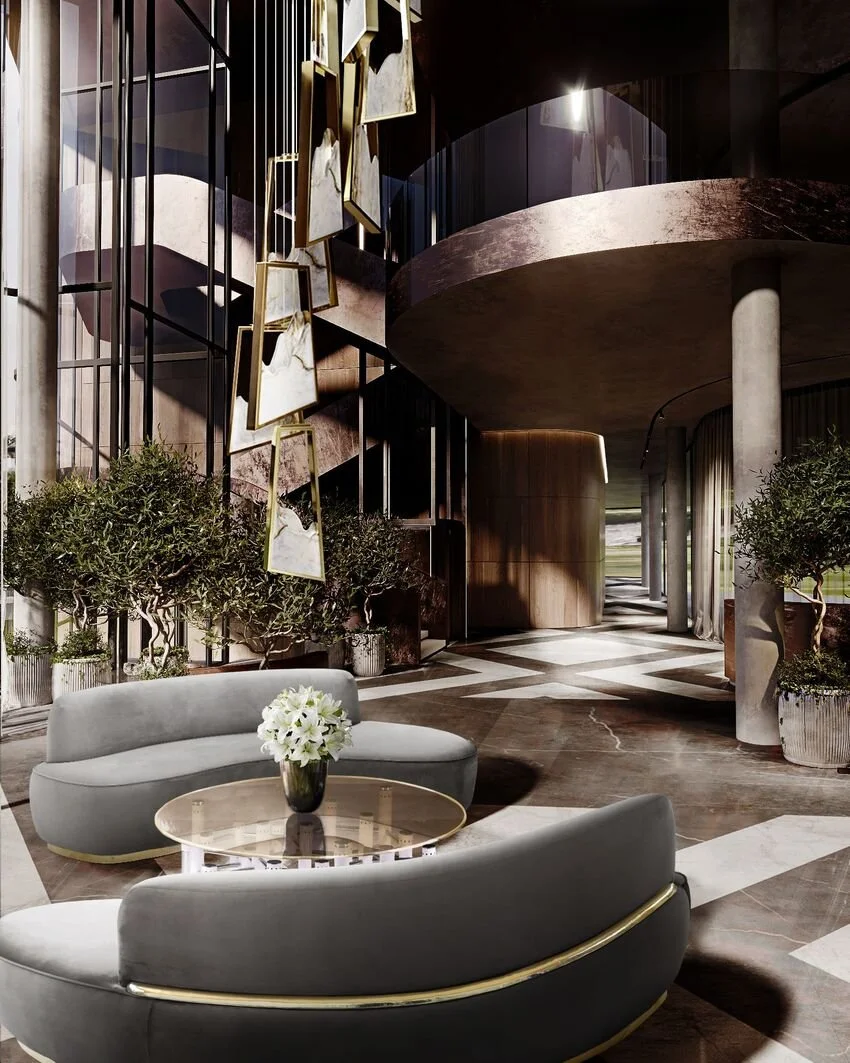 Modern hotel lobby with curved furniture, hanging gold photo frames, and potted trees. The space features a marble floor, large windows, and a high ceiling with a curved balcony.