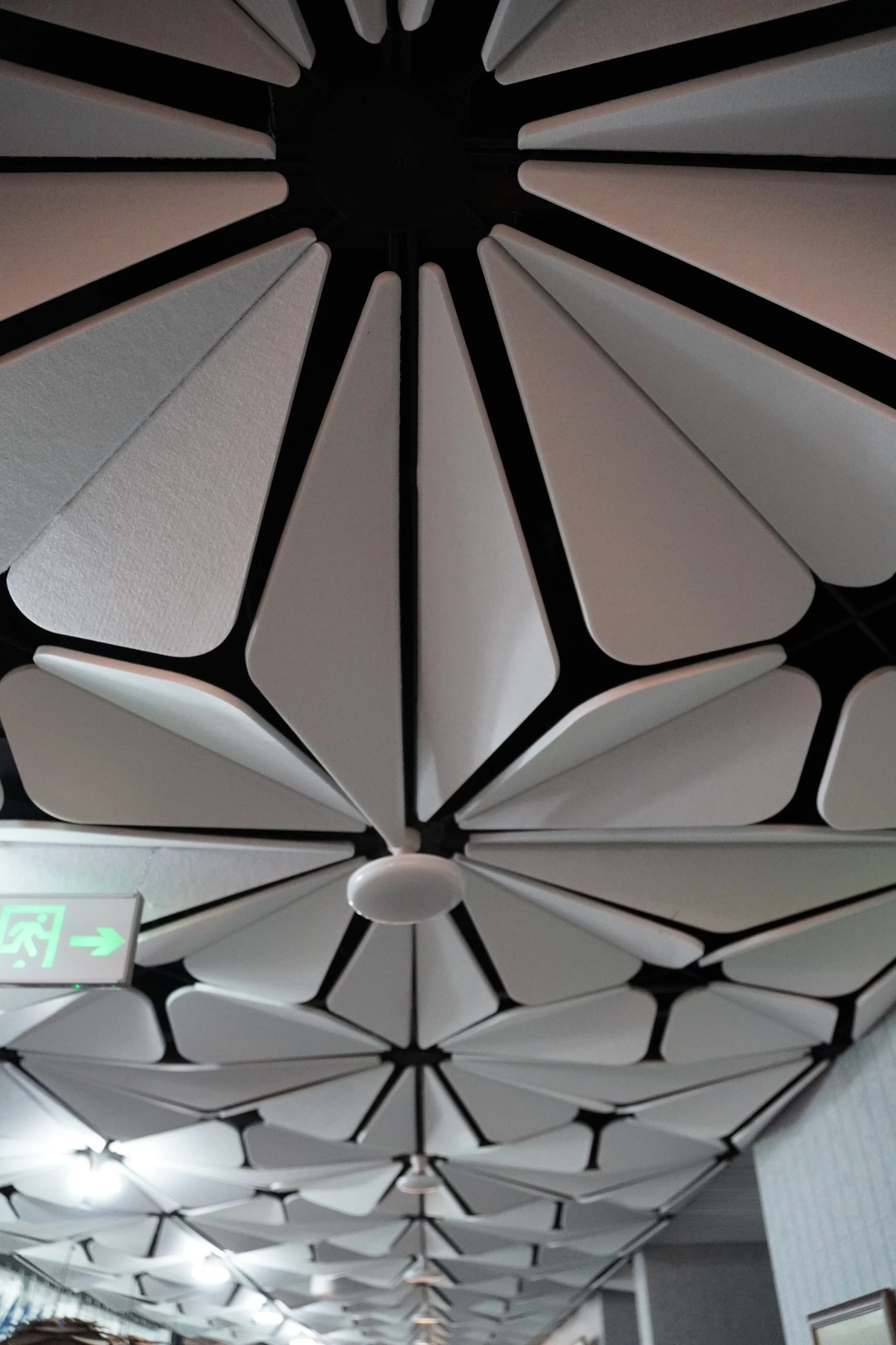 Ceiling with unique white, petal-shaped acoustic panels arranged in a patterned sequence.
