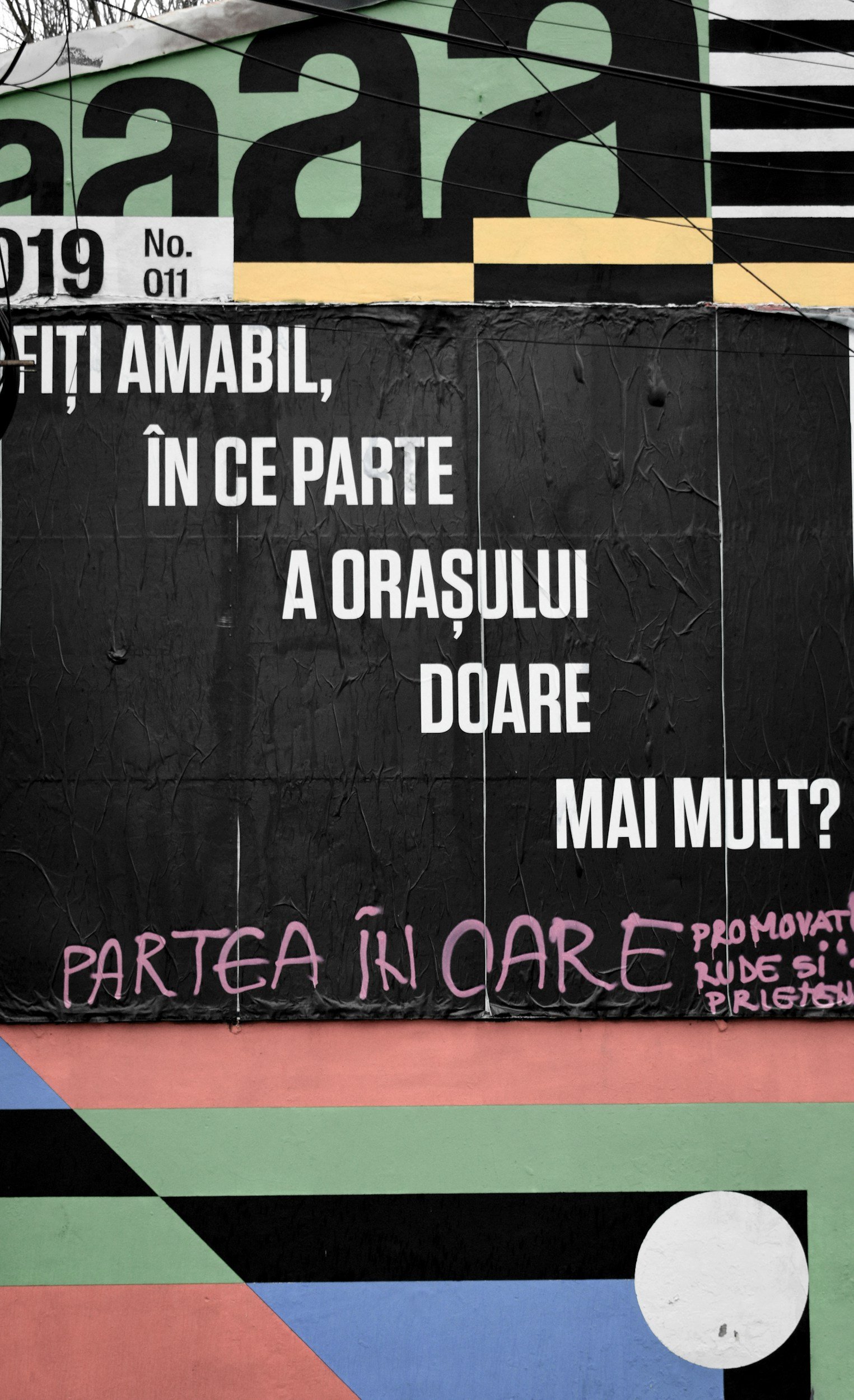 A black poster with white text questioning if the city is more beautiful in certain areas, with pink handwritten text promoting neighborhood participation, set against a colorful geometric background.