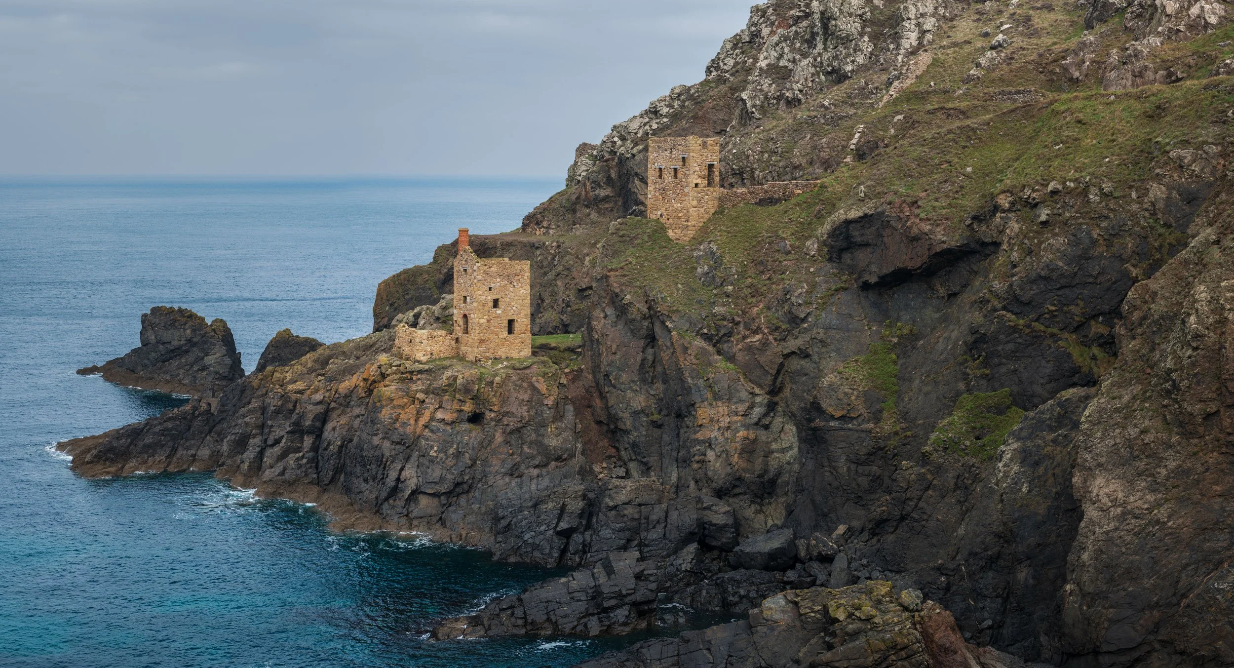 Old stone buildings on a rocky cliff overlooking the ocean