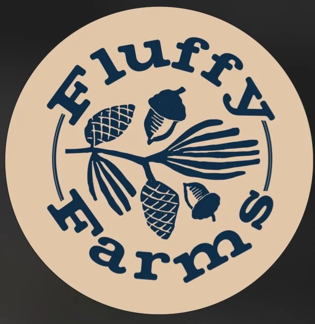Logo for Fluffy's Farm featuring a branch with pinecones, an acorn, and leaves in navy on a beige circular background.