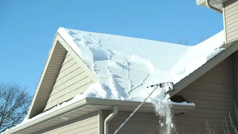A house with snow on its roof and a roof rake removing snow from the edge.
