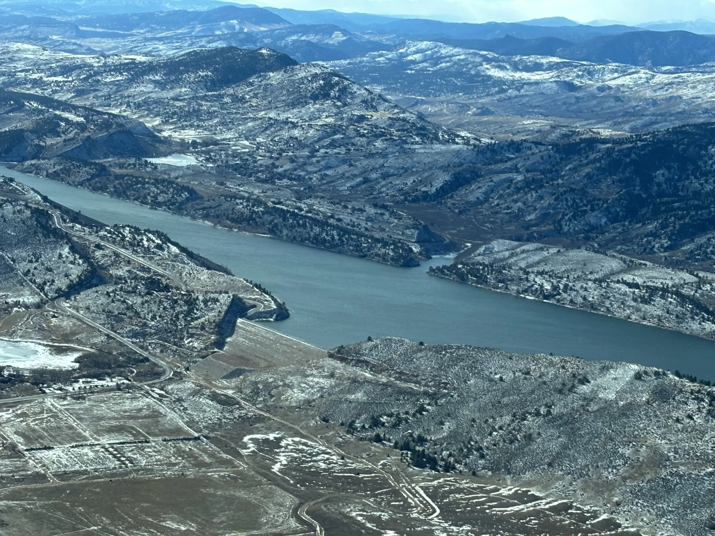 Aerial view of a large river winding through snow-covered hills and mountains.