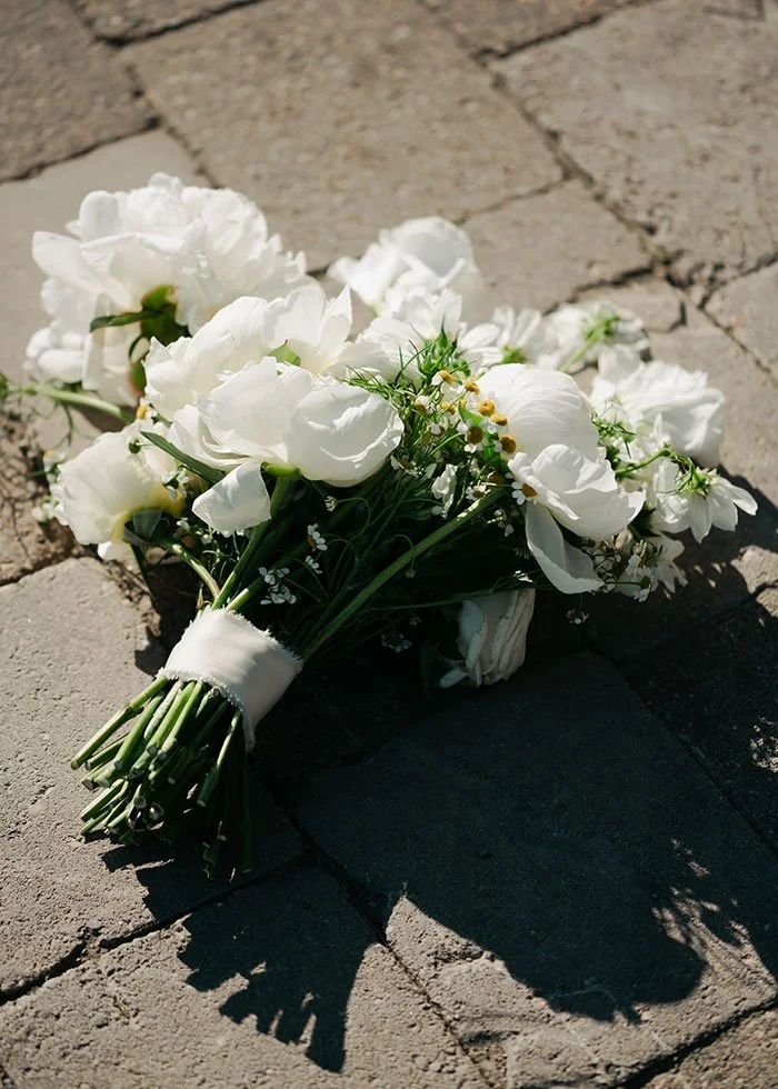 A bouquet of white wedding flowers lying on a cobblestone sidewalk in Montana.