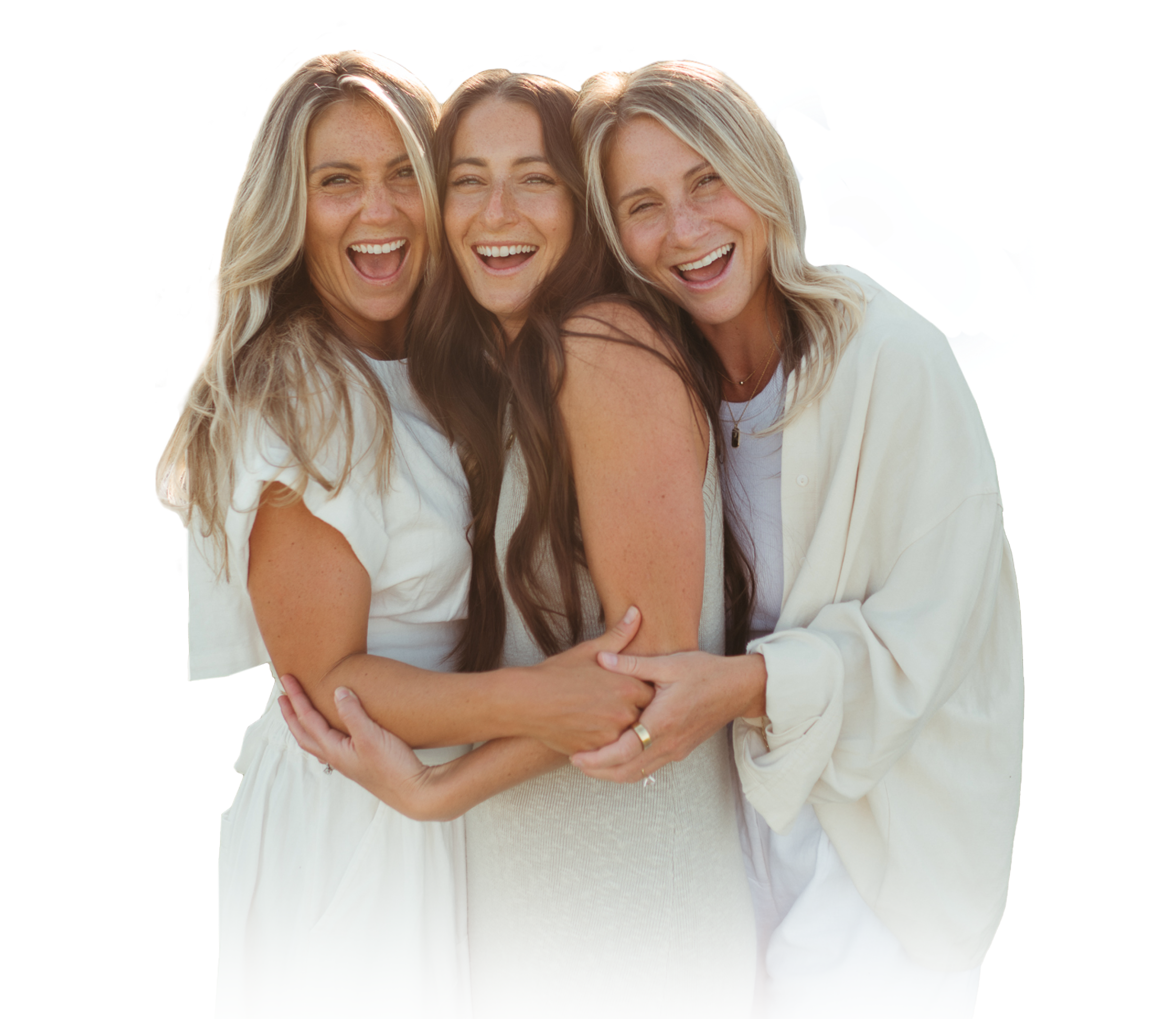 Three women smiling and hugging each other outdoors, wearing light-colored clothing.