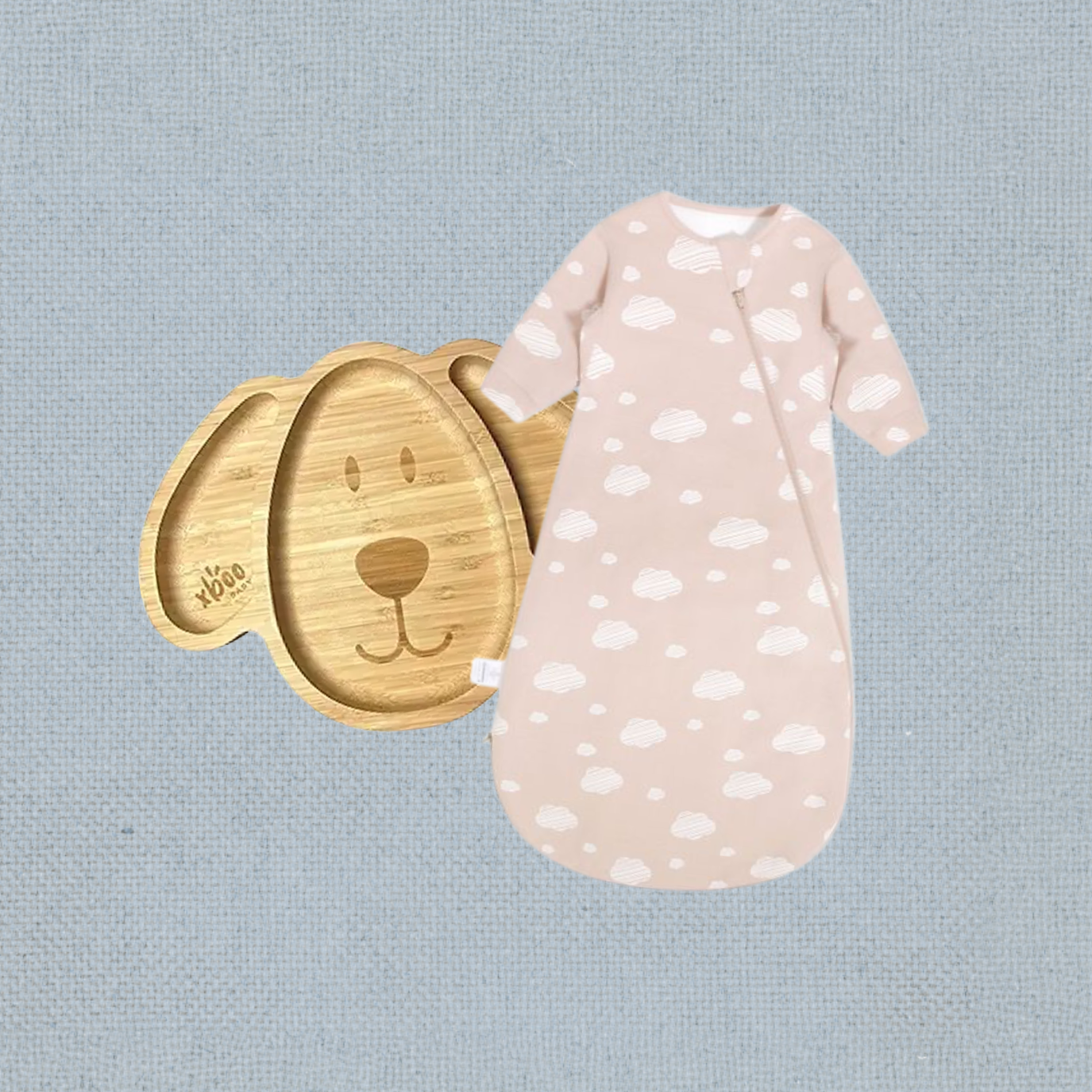 A wooden dog-shaped dish next to a pink baby sleeping bag with a white cloud pattern, placed on a gray textured surface.