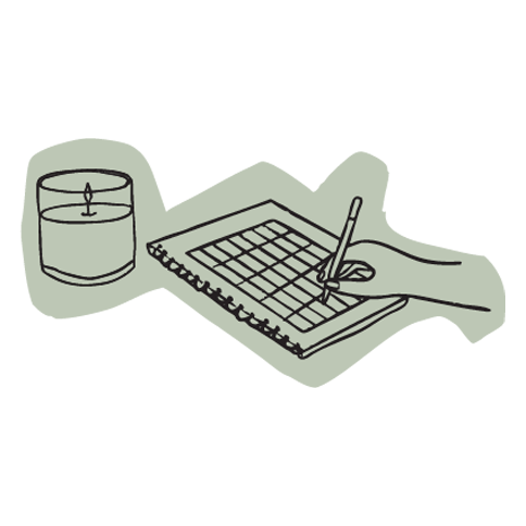 A hand holding a stylus writing on a journal, with a lit candle nearby on a table.